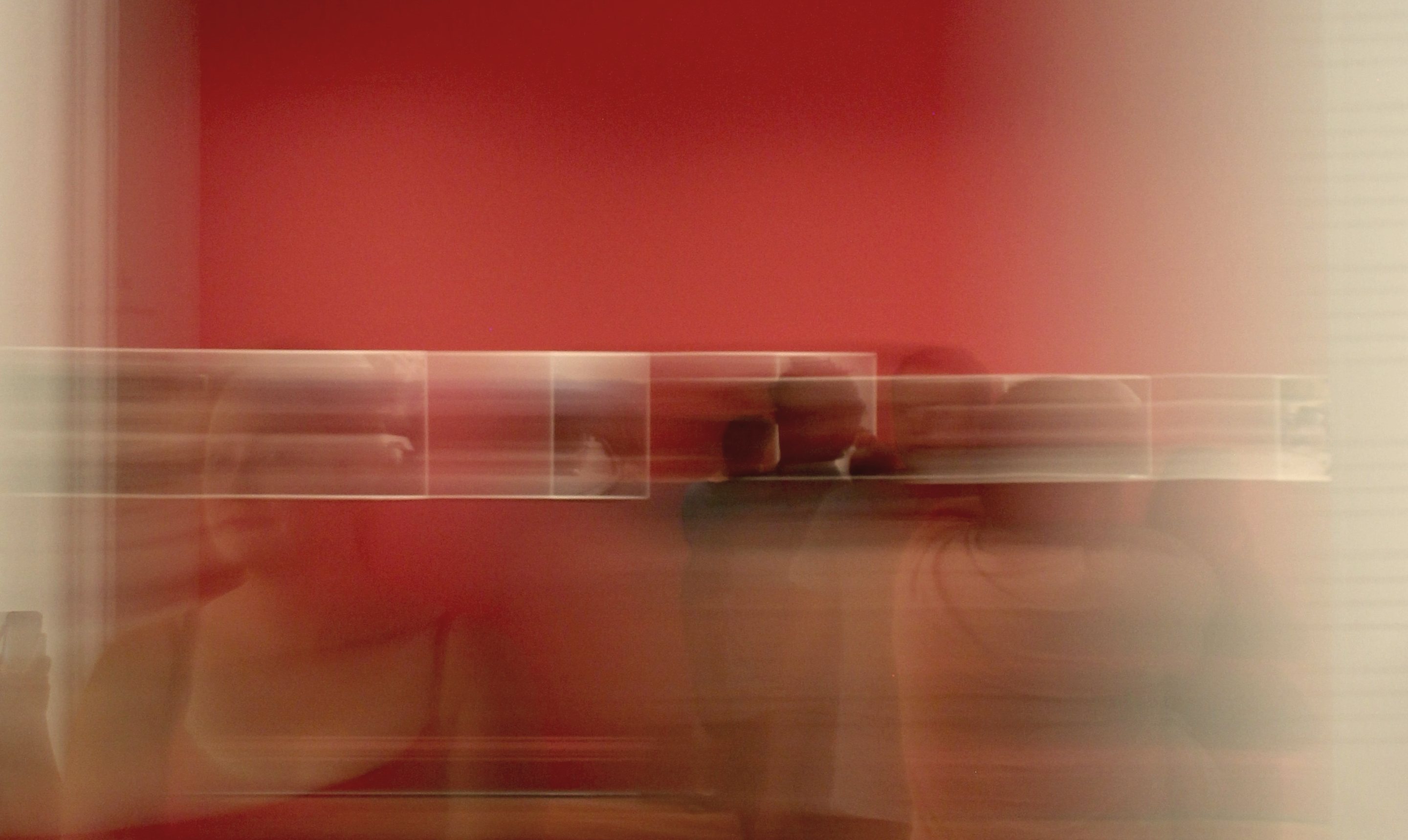 Blurred visitors moving through a red gallery room